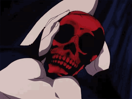 a person is holding a red skull with their hands