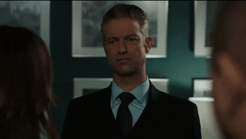 a man in a suit and tie looks at a woman