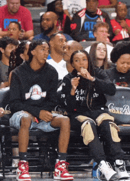 a man and a woman sit in the stands at a basketball game wearing all dream team shirts