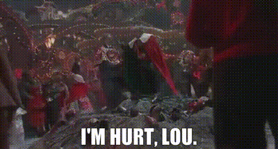 a group of people are standing in a dark room with the words `` i 'm hurt , lou '' written on the screen .