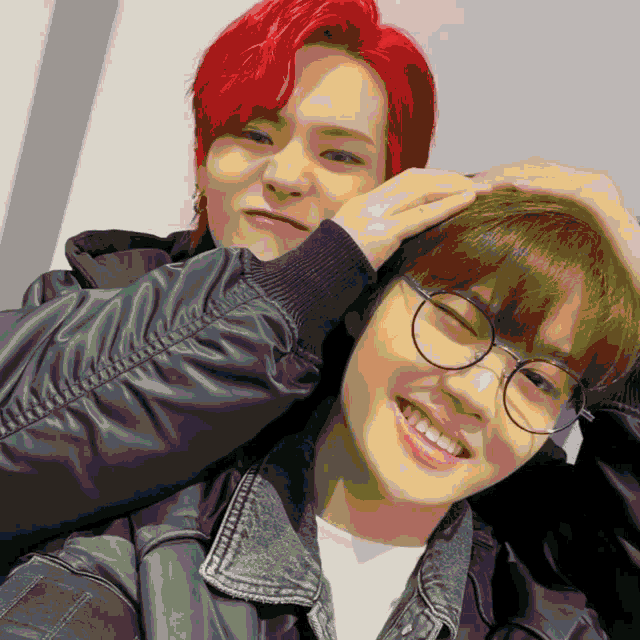 a boy with red hair is putting his hand on the head of another boy with glasses