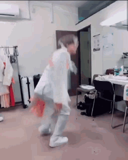 a person in a white coat is dancing in a dressing room .