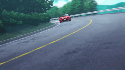 a red car is driving down a curvy road with trees in the background
