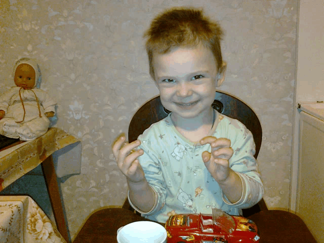 a little boy is smiling while holding a toy car