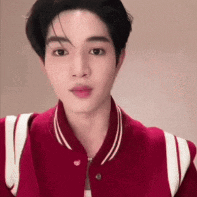 a close up of a young man wearing a red jacket and looking at the camera .