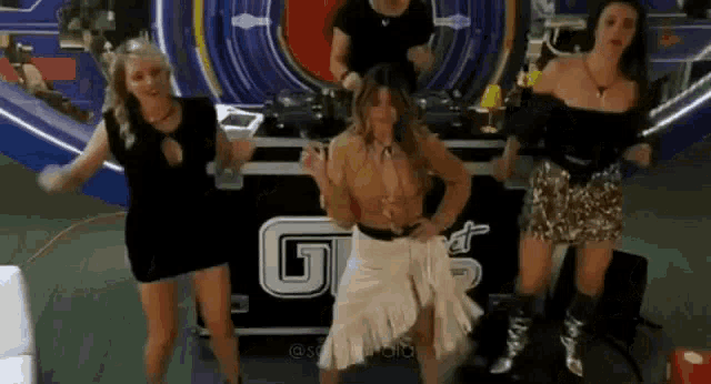 a group of women are dancing in front of a dj booth in a club .