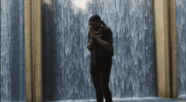 a man standing in front of a waterfall wearing a t-shirt that says ' a.f.f. '