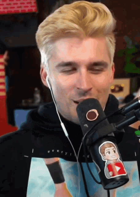 a man wearing headphones and a shirt that says ' i every ' on it is singing into a microphone