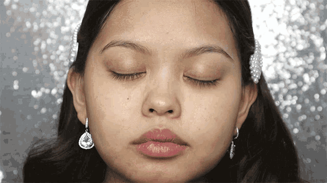 a close up of a woman 's face with her eyes closed and earrings