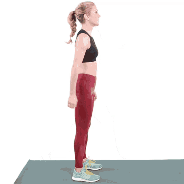 a woman in a black top and red leggings is running on a yoga mat