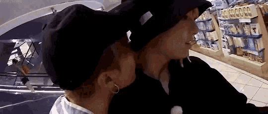 a man and a woman are kissing in a store while wearing hats .