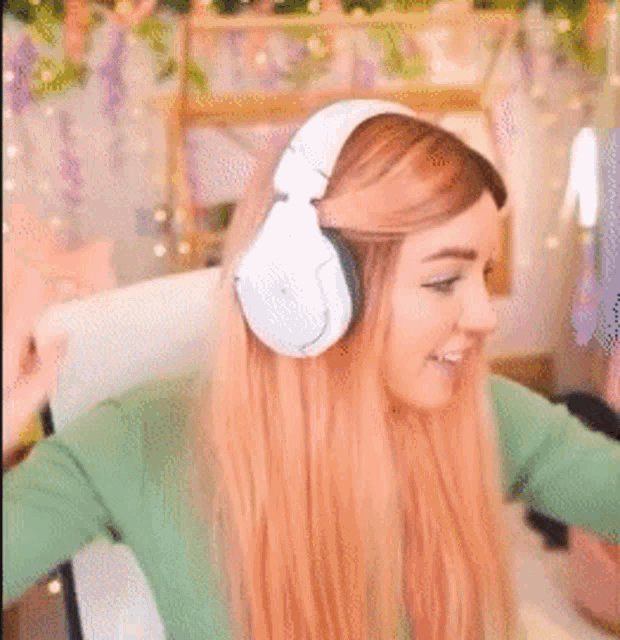 a woman wearing headphones and a green shirt is sitting in a chair with her arms outstretched .