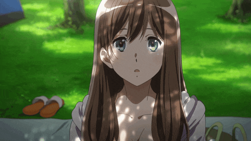 a girl with long brown hair is sitting on a blanket in the grass