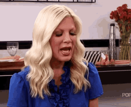 a woman in a blue shirt is making a funny face .