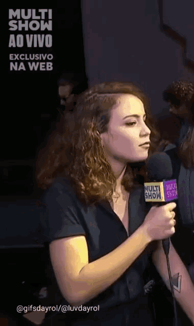 a woman is holding a microphone with the word multi show on it