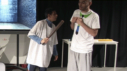 a man in a white shirt with a green tie is standing next to another man holding a bat