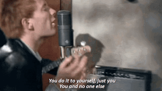 a man singing into a microphone with the words " you do it to yourself just you you and no one else " next to him
