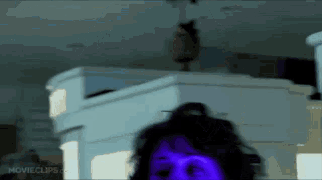 a woman with purple eyes is standing in front of a piano in a movie clip