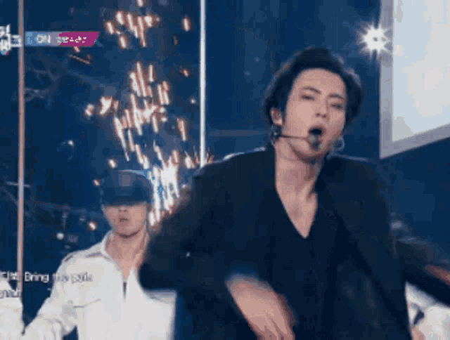 a man with a microphone in his mouth is dancing on a stage .