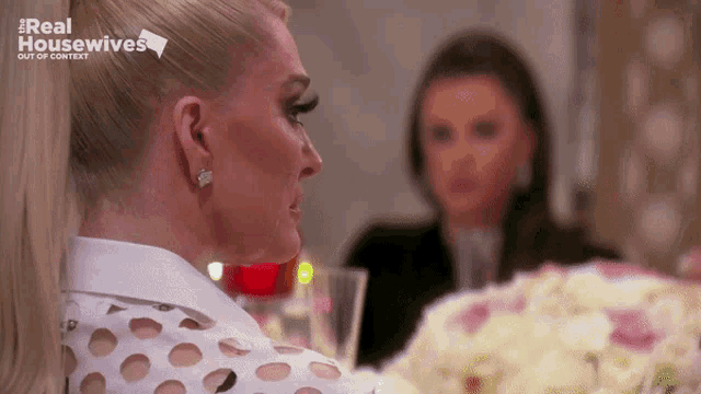 two women are sitting at a table with the words real housewives on the bottom