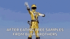 a yellow power ranger is waving in the rain while wearing a helmet .
