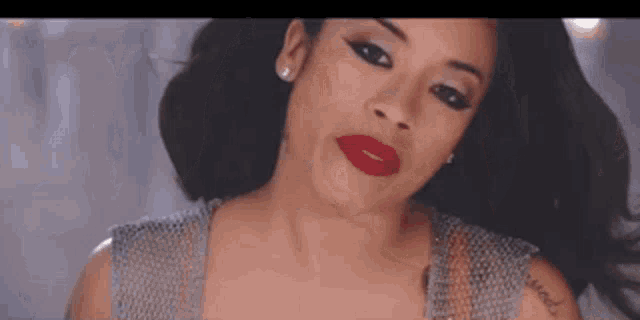 a close up of a woman 's face with red lipstick and a tattoo on her arm .