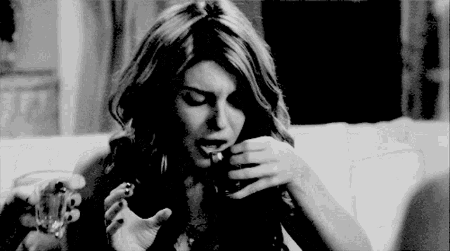 a woman smoking a cigarette while holding a glass of wine