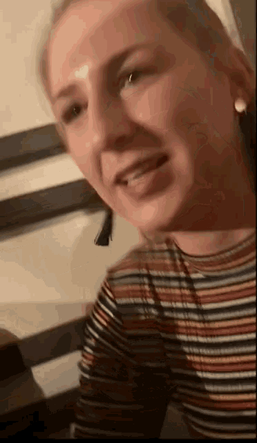 a woman wearing a striped shirt is smiling and looking at the camera