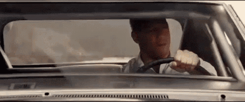 a man is driving a car on a dirt road .