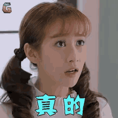 a girl with pigtails is making a surprised face and has chinese writing on her shirt .