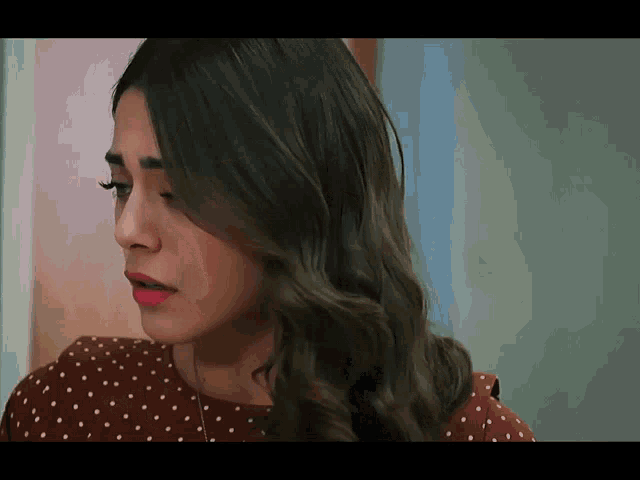 a close up of a woman 's face wearing a polka dot shirt