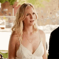 a woman in a white dress is standing next to a man and looking at the camera .