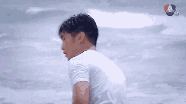 a man in a white shirt is standing on a beach near the water .