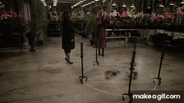 two women standing around a pentagram with make a gif.com on the bottom right