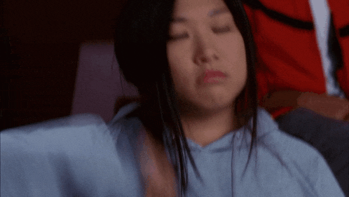 a woman with her eyes closed is wearing a blue hoodie