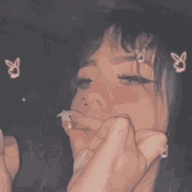 a girl is smoking a cigarette and blowing smoke into the air .