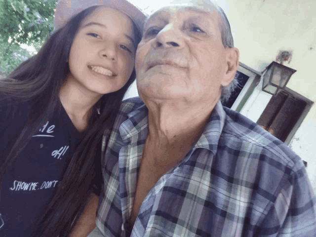 a girl wearing a shirt that says " how me do n't " stands next to an older man in a plaid shirt