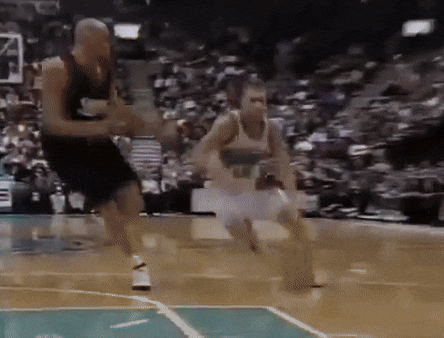 two men are playing basketball on a court with a crowd in the stands