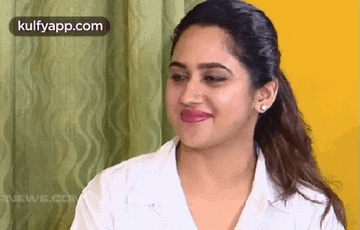 a woman in a white shirt is smiling and making a face .