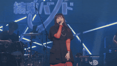 a woman singing into a microphone in front of a drum set that says yamaha