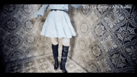 a woman in a blue skirt and black boots stands in front of a tiled wall ..