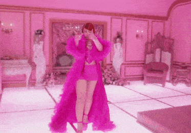 a woman in a pink outfit is standing in a room with pink walls