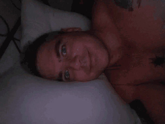 a shirtless man with a tattoo on his chest laying in bed