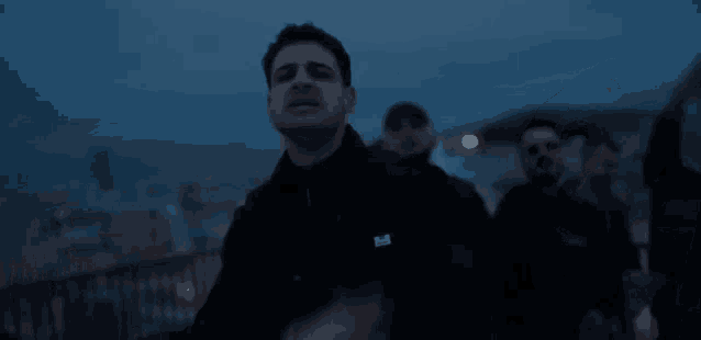 a group of men are standing in a dark room with their arms in the air .