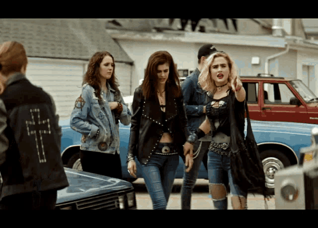a woman wearing a denim jacket with a cross on it stands next to three other women