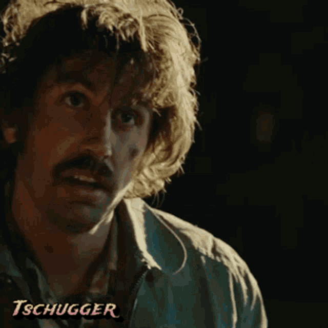 a close up of a man with a mustache and the word tschugger behind him