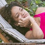 a woman in a pink top is laying on a chair with her hand on her face