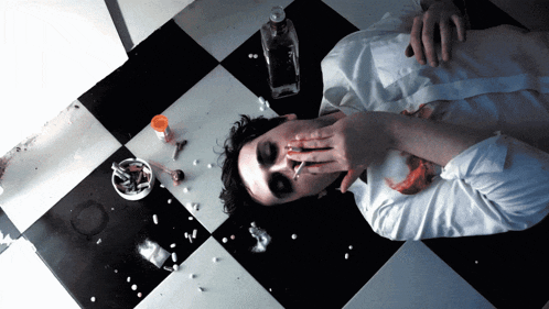 a man laying on a checkered floor with a cigarette in his mouth