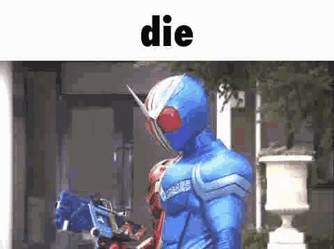 a man in a blue superhero costume is standing in front of a building and holding a gun .