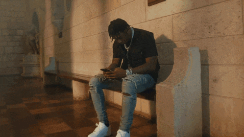 a man sitting on a bench looking at his cell phone